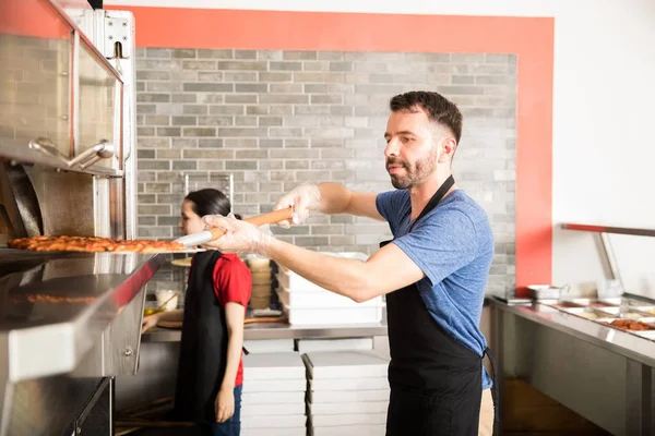 Chef Bonito Vestindo Avental Preto Removendo Pizza Assada Forno Usando — Fotografia de Stock