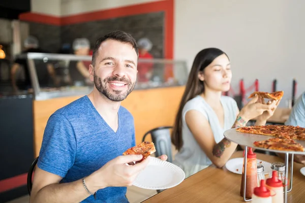 Retrato Joven Guapo Sosteniendo Una Rebanada Pizza Pepperoni Mano Sentado —  Fotos de Stock