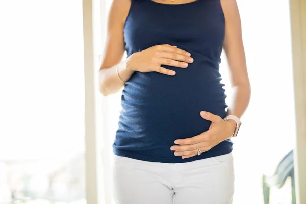 妊産婦家庭で胎動を感じるようにおなかに触れる女性の中央部 — ストック写真