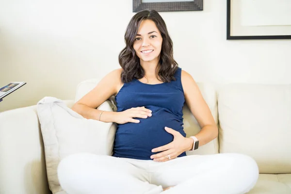 Hermosa Joven Embarazada Tocando Vientre Sonriendo Mientras Relaja Casa — Foto de Stock