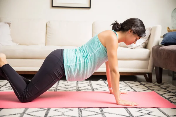 妇女在她怀孕期间做俯卧撑在家庭锻炼垫的侧面看法 — 图库照片