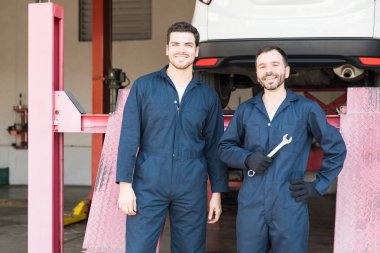 Garajda ayakta tulumlu yetişkin araba mekaniği orta emin