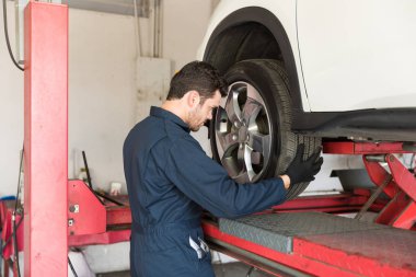 Orta yetişkin Otomotiv işçisi bir araba garajında lastik değiştirme