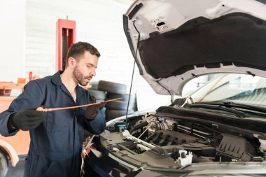 Orta yetişkin erkek mühendis Atölyesi'nde rutin bakım sırasında yağ seviyesi araba motoru kontrol