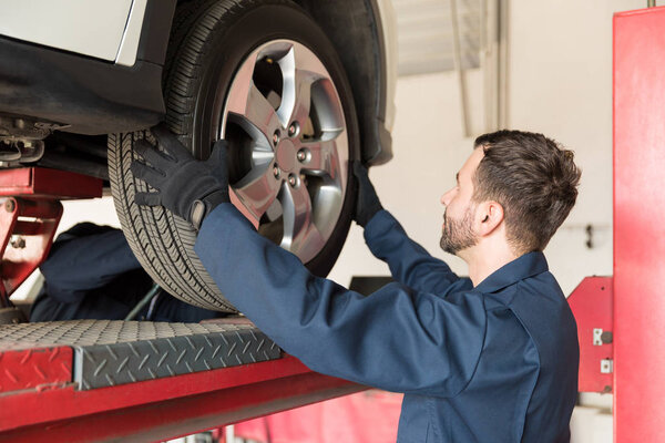 Side view of male mechanic replacing car tire at auto repair shop
