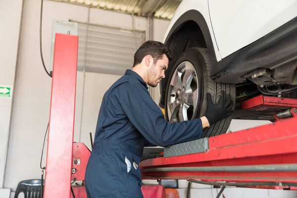 Side view of auto mechanic adjusting car tire in repair shop