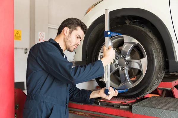 维修工程师在车库中用弧形脚轮适配器检查轮胎的对准 — 图库照片