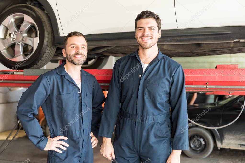 Portrait of confident male mechanics smiling in auto repair shop
