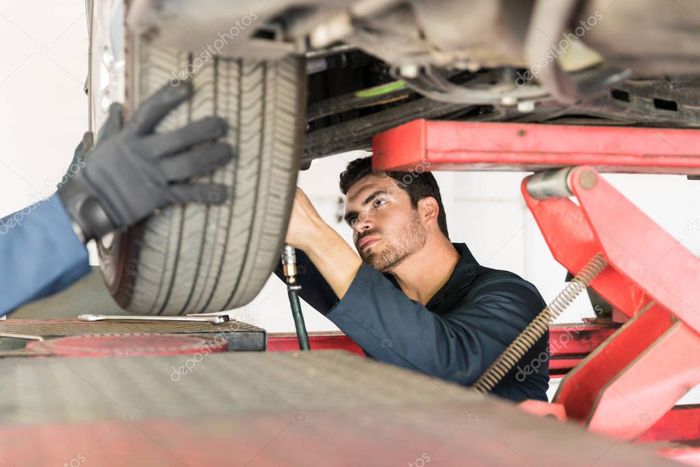 Concentrated mechanic repairing car tire in auto repair shop