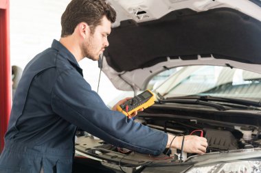 Otomatik mekanik Atölyesi'nde dijital multimetre test araba pil ile yan görünüm