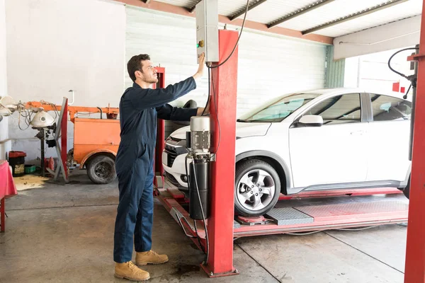 Full Length Mid Adult Car Mechanic Operating Hydraulic Lift Repair — Stock Photo, Image