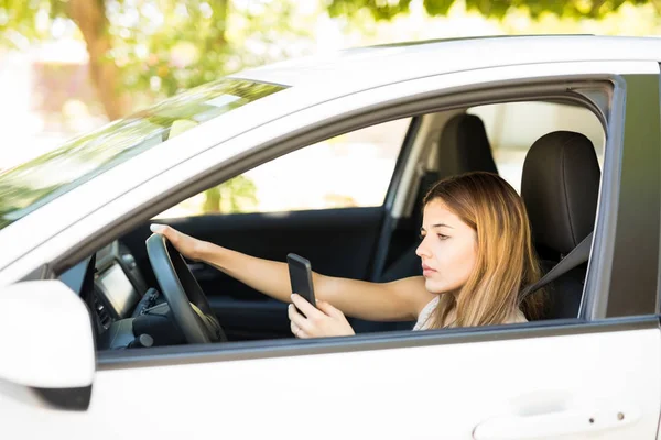 Młoda Kobieta Przyjmuje Wiadomości Podczas Jazdy Samochodem Przy Użyciu Telefonu — Zdjęcie stockowe