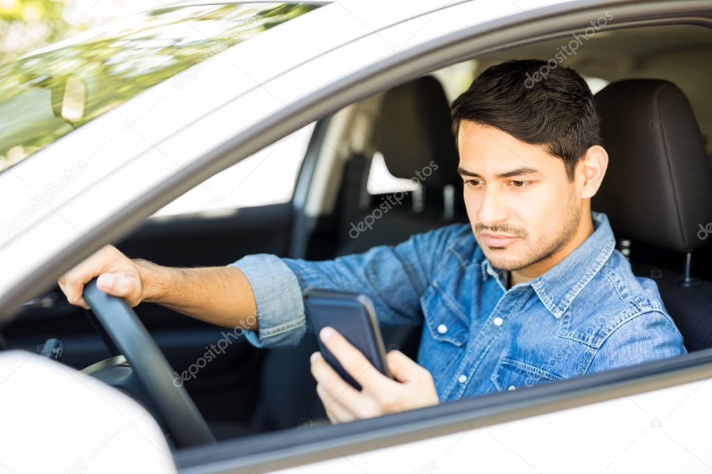 Portrait of reckless male driver using his mobile phone behind the wheel