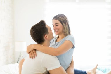 Çok ırklı mutlu çift yatakta evde otururken romancing
