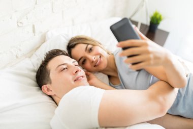 Kadının onu evde yatakta kucaklayan adam akıllı selfie alarak yüksek açılı görünüş