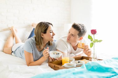 Erkek ve kadın tarafından evinde yatakta kahvaltı tepsisi yemek yerken söz