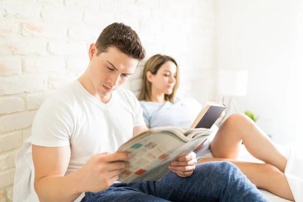 ハンサムな男性女性の自宅のベッドの上に座って新聞を読む — ストック写真