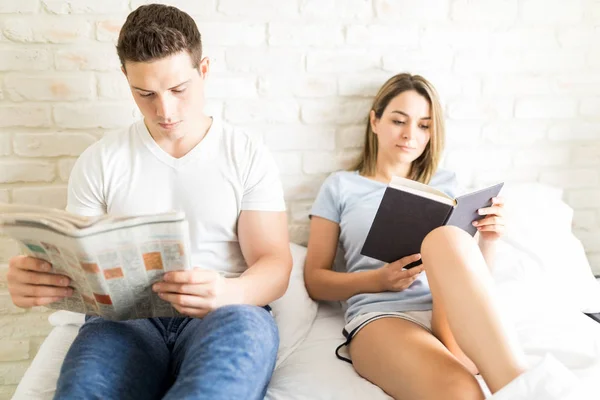夫妇阅读报纸和日记在床上公寓 — 图库照片