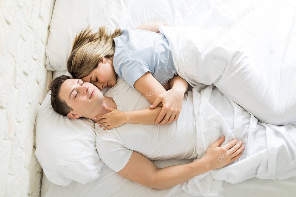 Directly above shot of couple having a nap together on bed at home