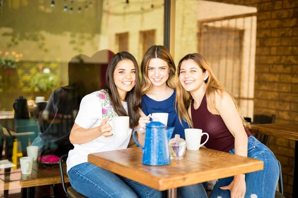 三位女性朋友的肖像在餐馆与杯子咖啡 — 图库照片