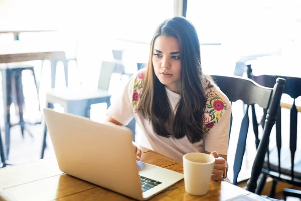 有吸引力的拉丁妇女的画像坐在咖啡馆和冲浪互联网在 Lapto — 图库照片