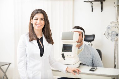 Adam hasta oturan göz testi içinde geçmiş için göz hastalıkları kliniğinde stetoskop ayakta giyen güzel gülümseyen kadın portresi
