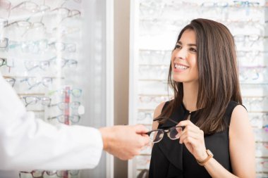 Çekici kadın gözlük ekran raf optik mağaza karşı denemek için gözlükçü elinden alarak