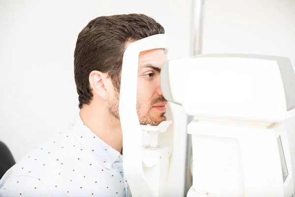 英俊的人检查他的视力在机器检查病人视力在眼科诊所 — 图库照片