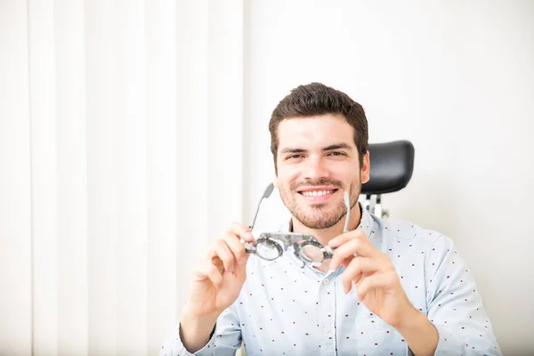 Portrait of happy man wearing trial frame in ophthalmological clinic