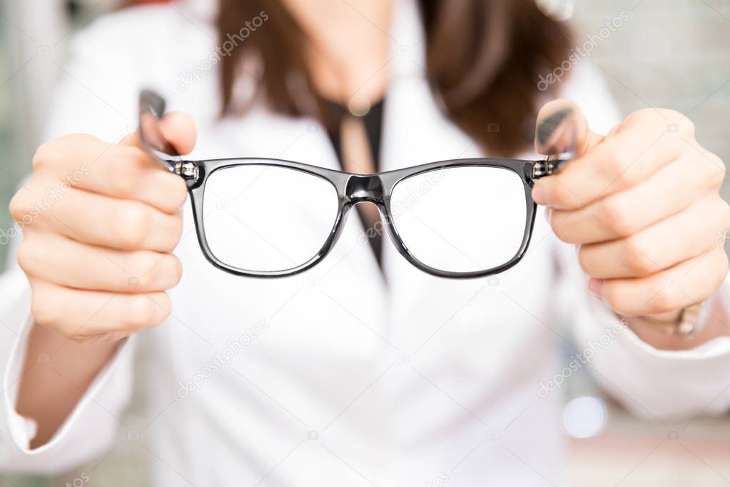 Close-up of woman optician holding trendy and new spectacles