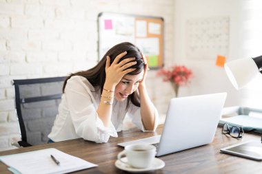 Kafasını tutarak ve Resepsiyon masasında laptop arıyorum stresli genç iş kadını portresi