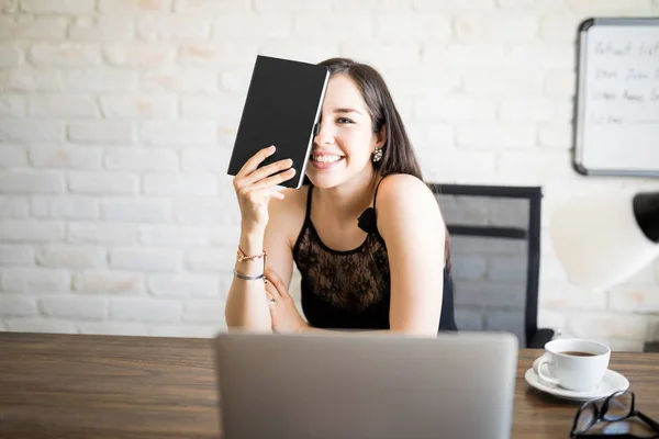 Retrato Una Joven Hispana Feliz Sentada Mesa Sosteniendo Libro Frente —  Fotos de Stock