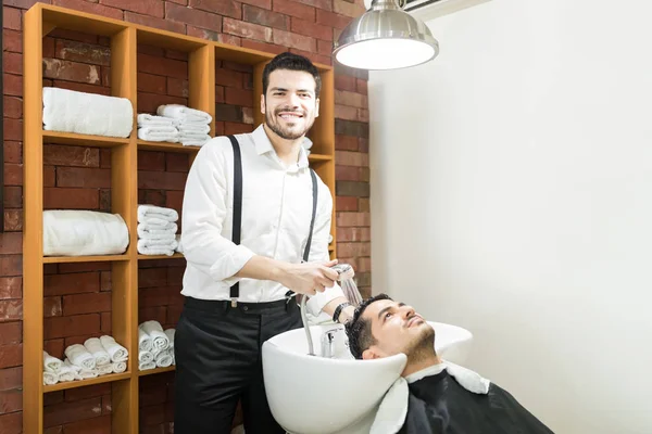 Confident Barber Smiling While Washing Customer Hair Shower Shop — Stockfoto