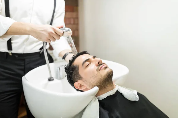 Joven Relajado Con Los Ojos Cerrados Apoyándose Lavabo Mientras Peluquera —  Fotos de Stock