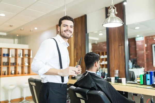 Estilista Masculino Confiado Sonriendo Mientras Arregla Cabello Del Cliente Peluquería —  Fotos de Stock