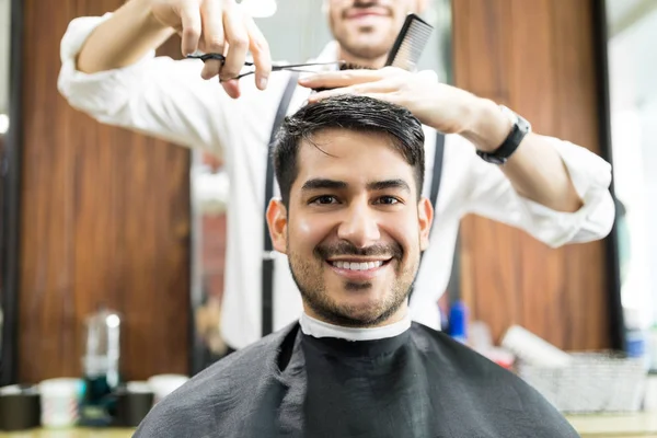Młody Mężczyzna Klienta Uśmiechający Się Podczas Pobierania Usługi Fryzjera Salonie — Zdjęcie stockowe