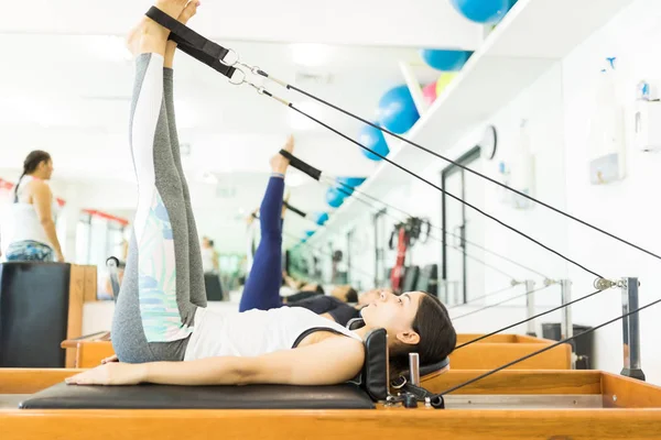 Kadın Müşteri Onun Fitness Salonunda Reformcu Makinede Egzersiz Yaparken Bakımı — Stok fotoğraf