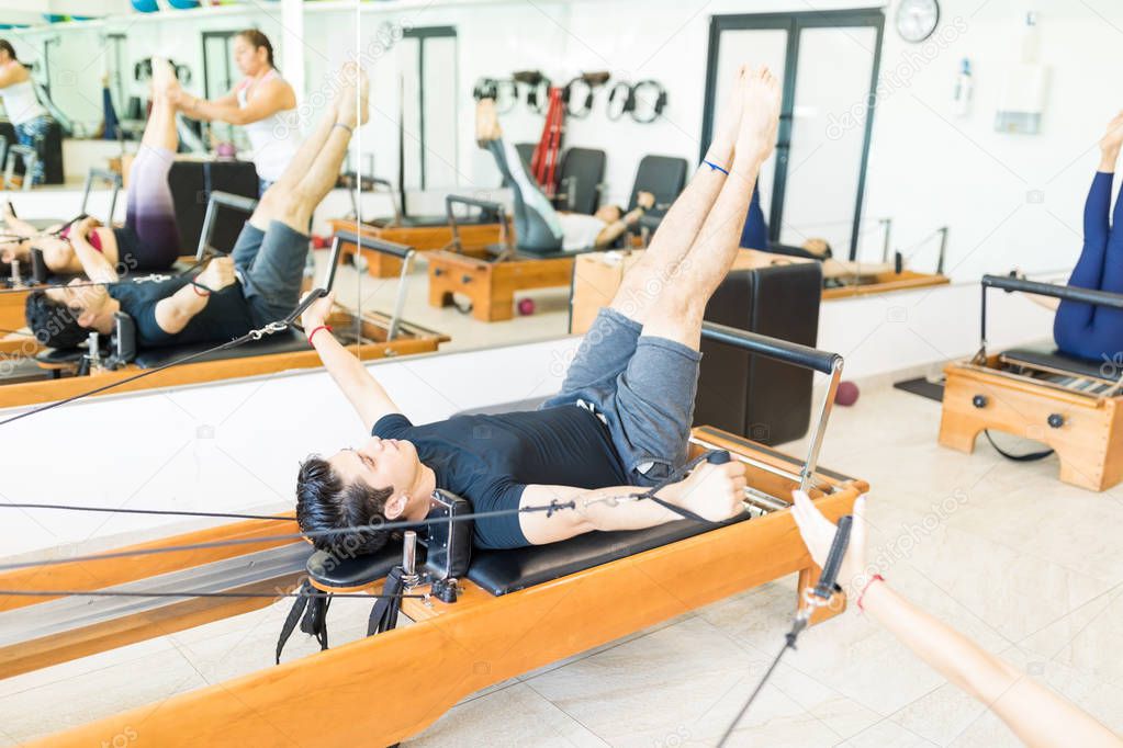 Determined young female on pilates reformer in gym