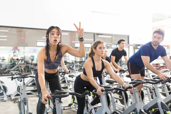 自信的男性客户微笑 而在自行车上与朋友在健身房运动 — 图库照片