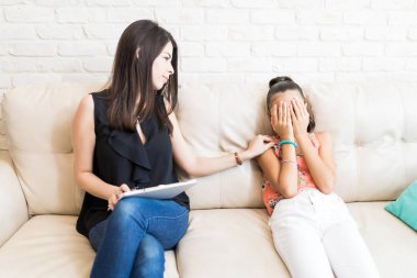 Üzgün kız kapsayan yüz evde kanepe üzerinde teselli orta yetişkin psikolog