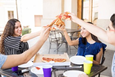 Mutlu genç erkek ve kızlar eğleniyor ve bir restoranda pizza yemek