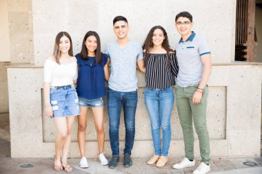 Beş genç arkadaşlar ayakta açık havada kollarını ile birlikte grup portresi