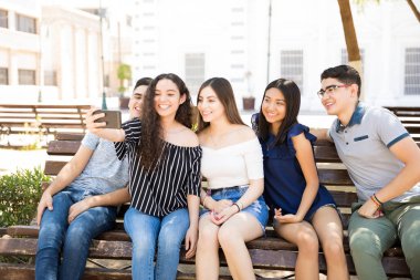 Genç erkek ve kız selfie açık havada bankta oturan alarak