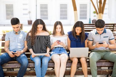 Genç erkek ve kızlar için sosyal ağ dizüstü bilgisayar, dijital tablet ve akıllı telefon gibi farklı cihazlar kullanarak