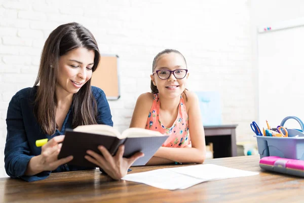 Smiling Little Girl Sitting Home Tutor Reading Book Table — Stock Photo, Image