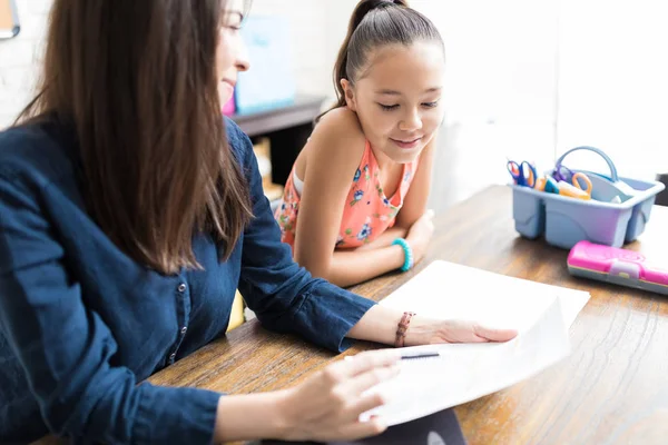 Chica Leyendo Sus Notas Sostenidas Por Maestra Mesa Casa — Foto de Stock