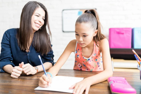 Sonriente Profesora Casa Adulta Mirando Una Estudiante Escribiendo Papel Mesa — Foto de Stock