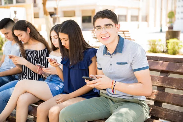 Sonriente Joven Sentado Banco Con Amigo Usando Sus Teléfonos — Foto de Stock