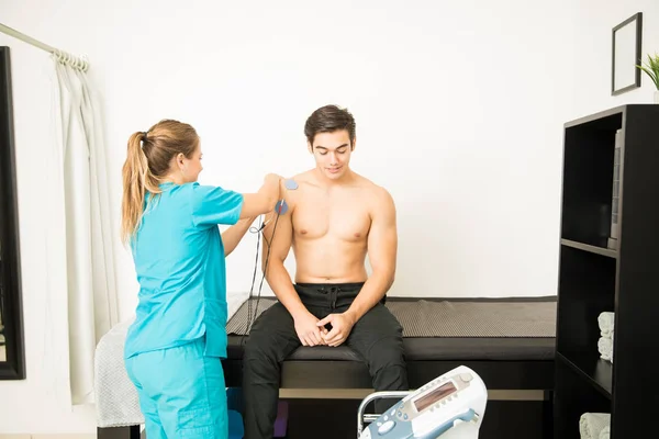 Joven Fisioterapeuta Preparando Paciente Masculino Para Electroterapia Hombro Clínica — Foto de Stock