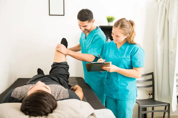 Молодые Физиотерапевты Проверяют Ногу Пациента Готовят Заметки Больнице — стоковое фото